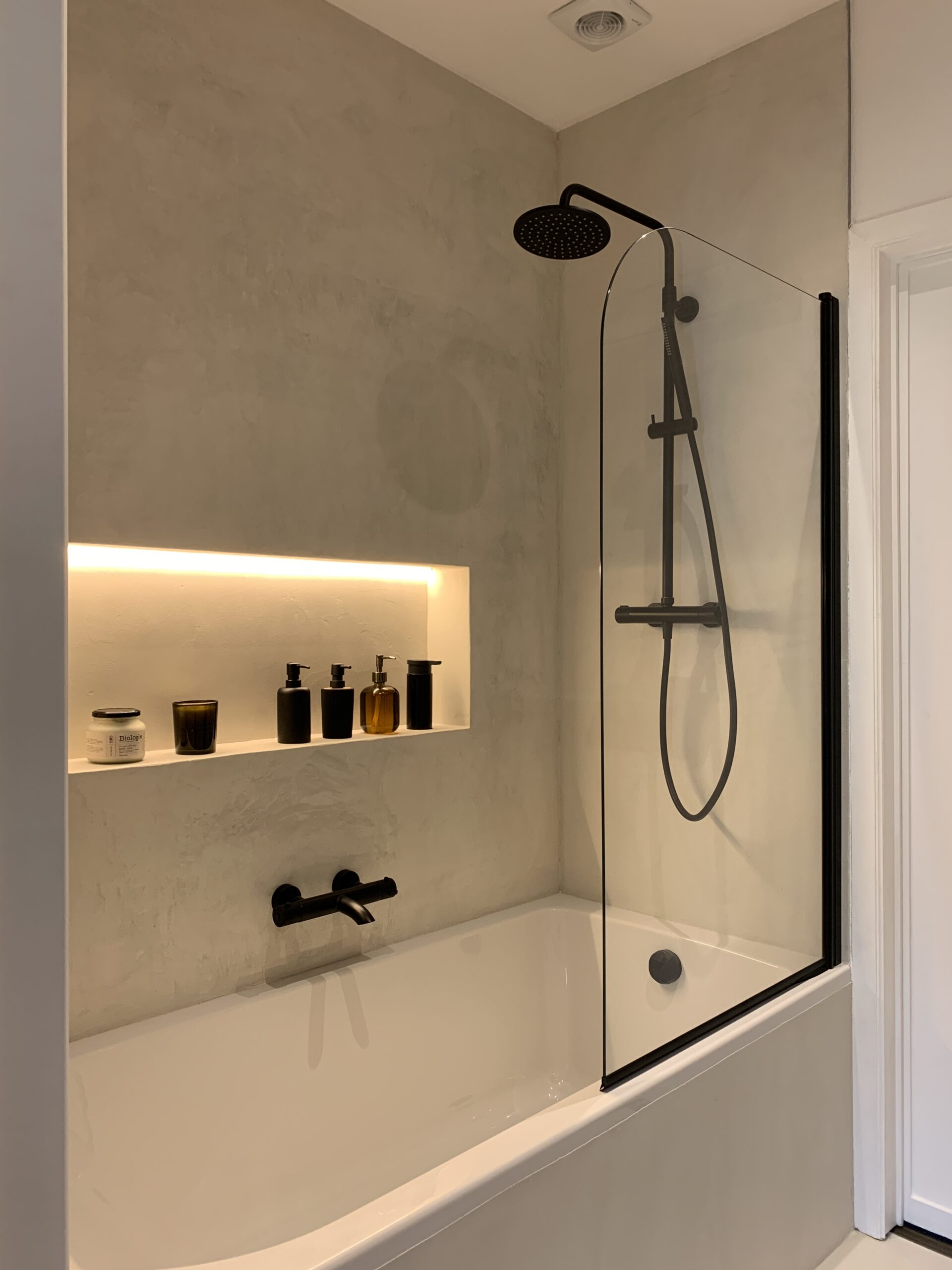 Douche et baignoire en béton ciré avec niche et robinetterie noire